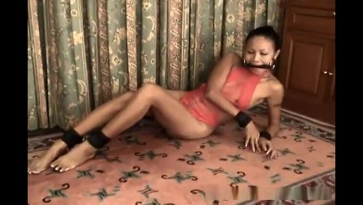 Ragazza asiatica snella in lingerie rossa, ammanettata e imbavagliata