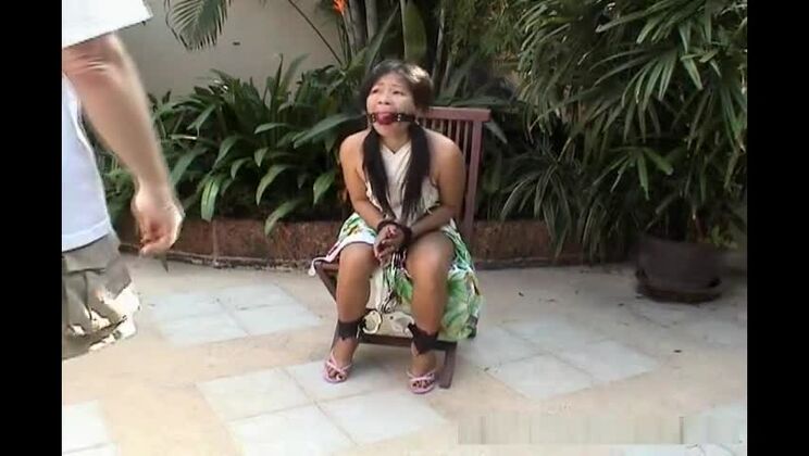 Una ragazza asiatica attraente immobilizzata su una sedia.